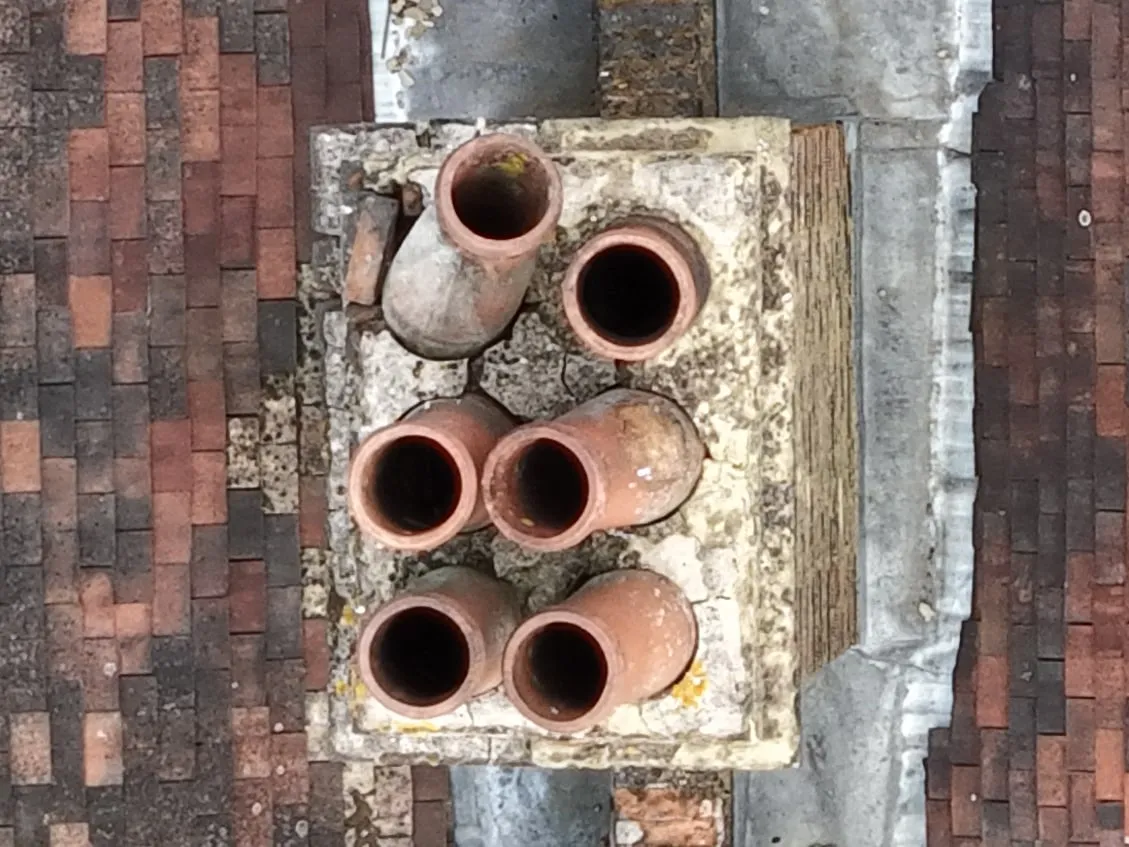 A chimney stack from above: five pots upright and one leaning over at a steep angle
