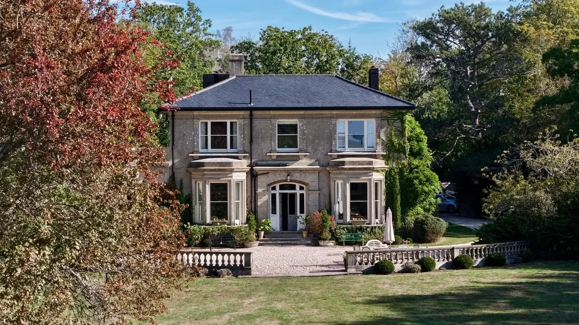 Ground-level view of a large period house with ivy-covered walls and a gravel forecourt